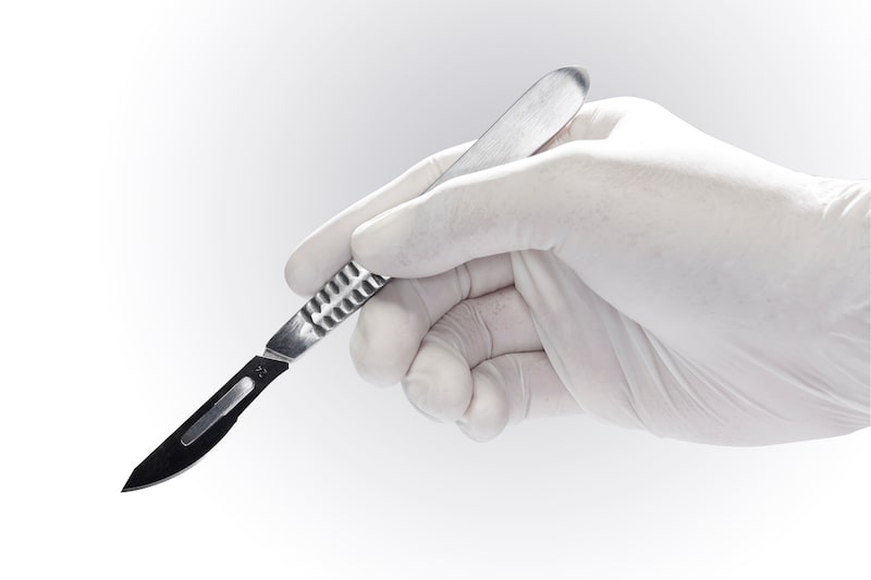 Surgeon holding a scalpel surgical blade.