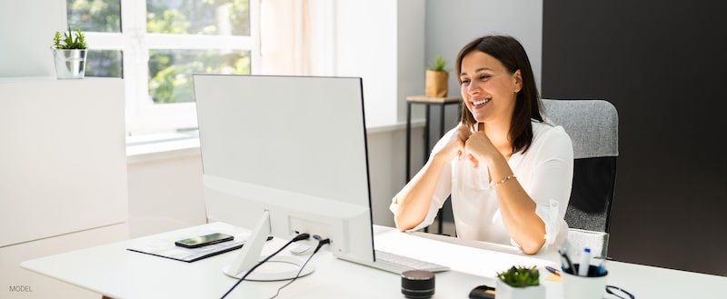Woman sitting at a computer monitor.